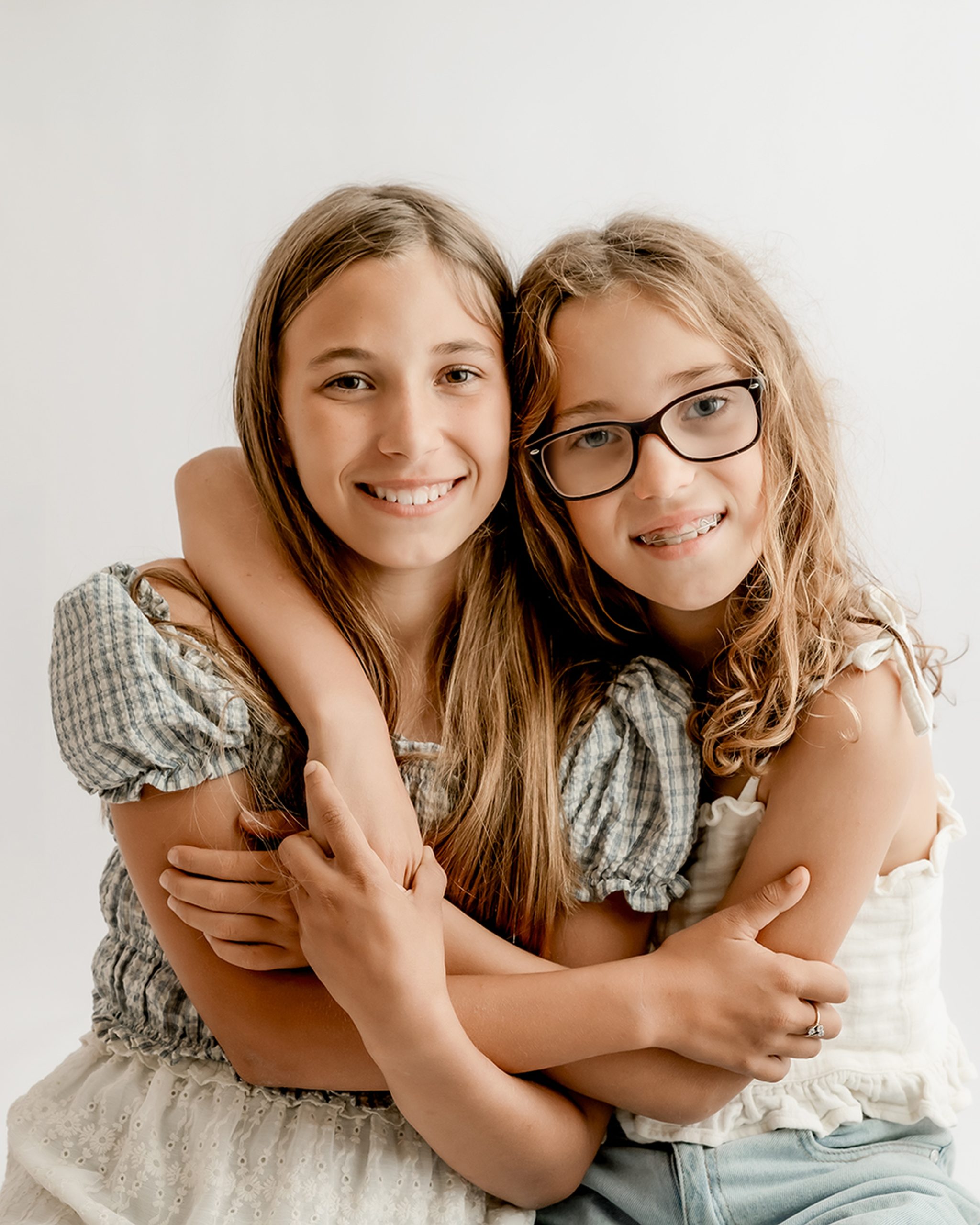 sisters hugging for a photo during sibling minis with mini studio